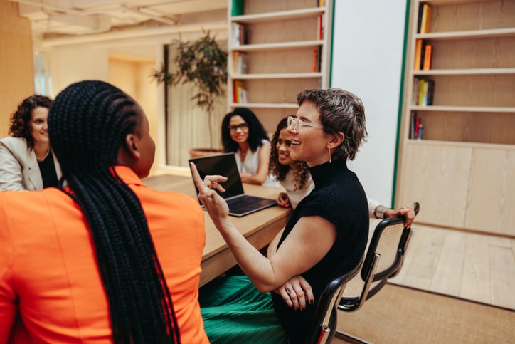 a group of women sit around a table talking to each other